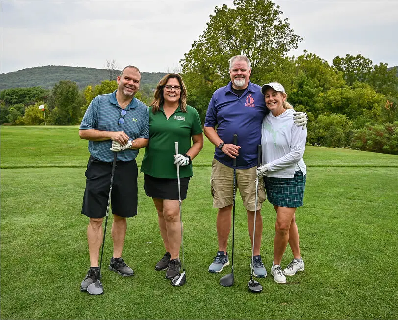 Four people posing together during a golf outing at The Great Gorge in Vernon, NJ, smiling and enjoying the event, with the golf course and scenic surroundings in the background.