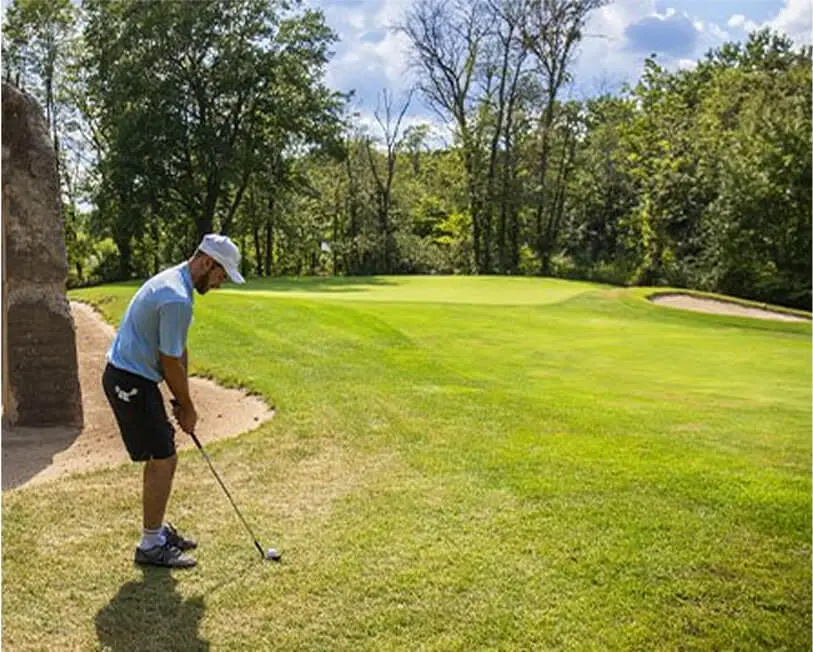 Man playing golf on a sunny day at The Great Gorge in Vernon, NJ, with bright green grass and clear blue skies.