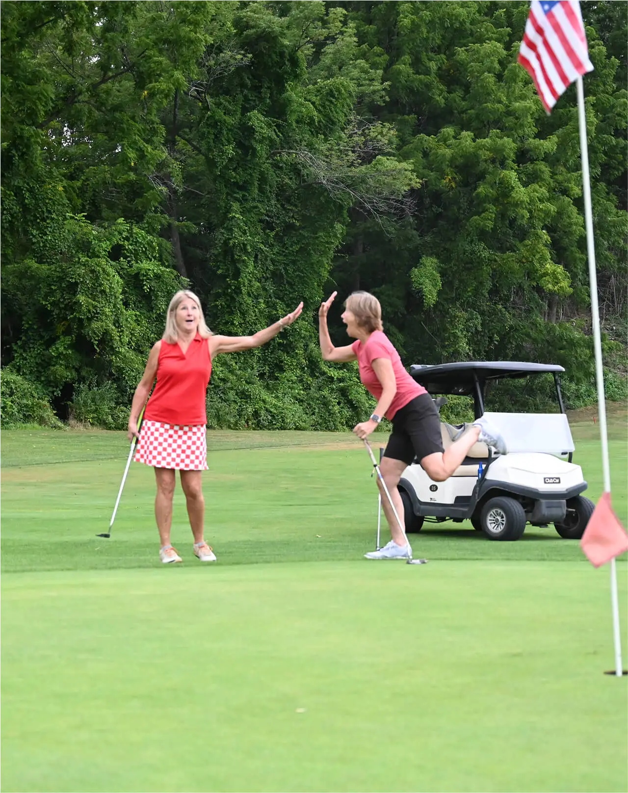 Two women high-fiving each other after a successful round at the Great Gorge Golf Club Ladies Golf League, celebrating their teamwork and camaraderie.