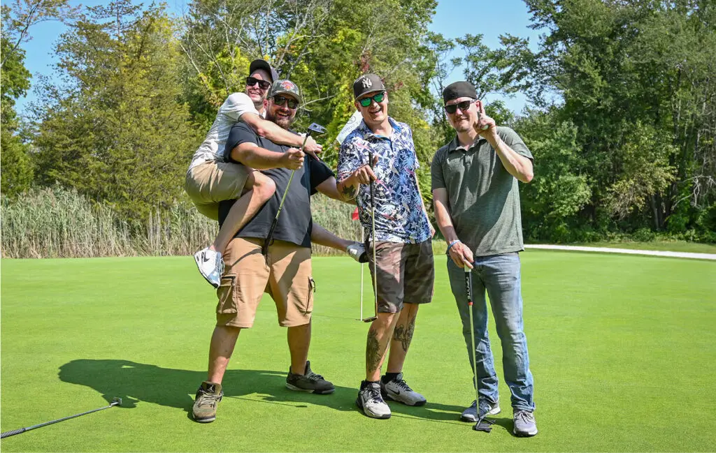 Group of men enjoying themselves at The Great Gorge in Vernon, NJ, as part of a group or corporate outing, laughing and engaging in friendly competition on the golf course.