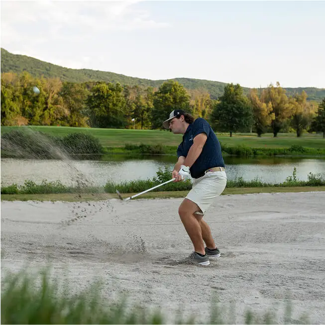 Man preparing to hit a golf ball at the Lake Course at The Great Gorge in Vernon, NJ, with the serene lake and lush fairways in the background.