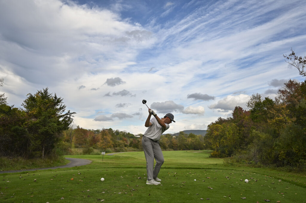 Golfer getting ready to swing at Great Gorge Golf Club during fall, with vibrant autumn trees in the background.